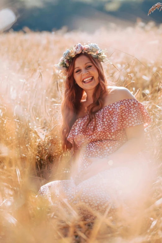 a woman in a dress sitting on top of a lush grass field