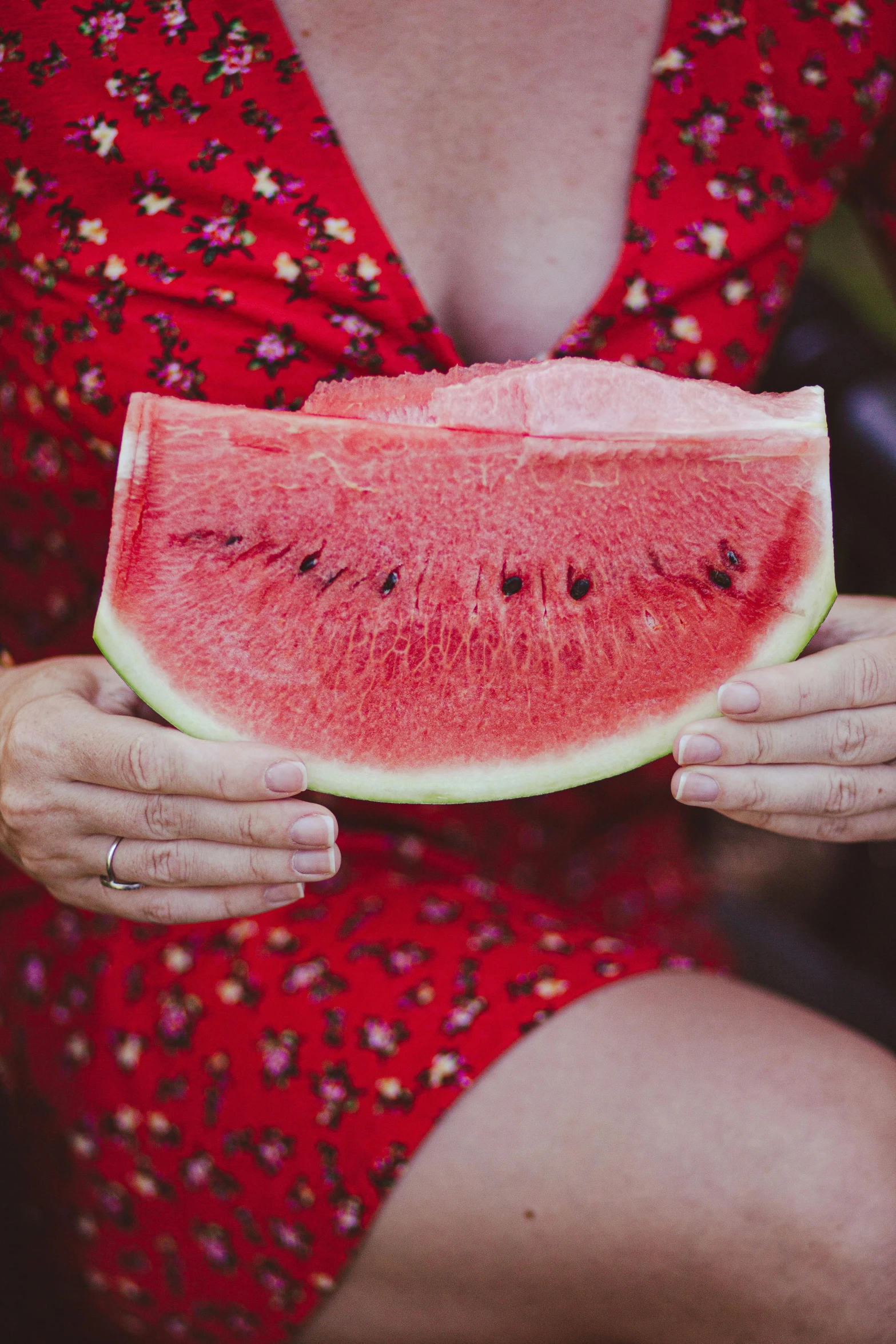 a person holding a large piece of watermelon