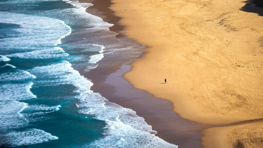 an aerial view of a beach with people walking along the shore and crashing waves