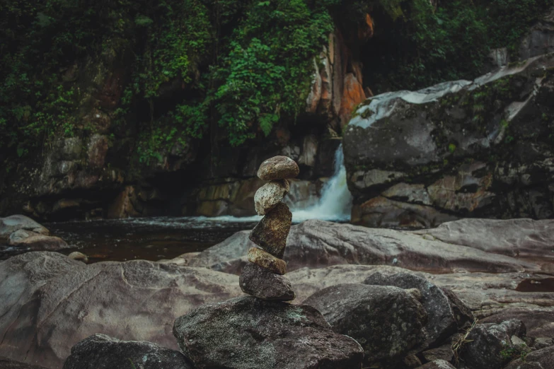 rock stacked into the form of a person standing on a riverbank
