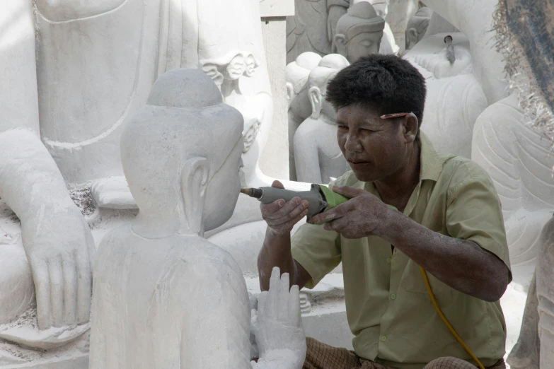 a man carving a piece of art using scissors