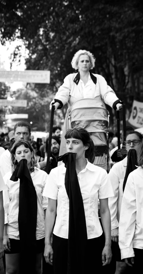 black and white pograph of a woman walking in front of a group of people