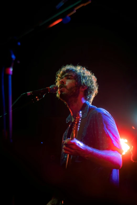 a man playing a guitar in front of a microphone