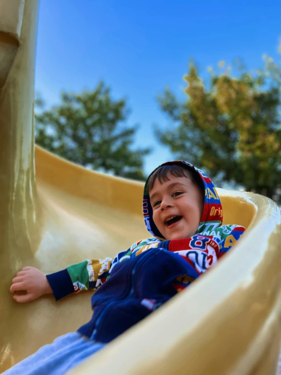 a smiling boy playing on the slide in the park