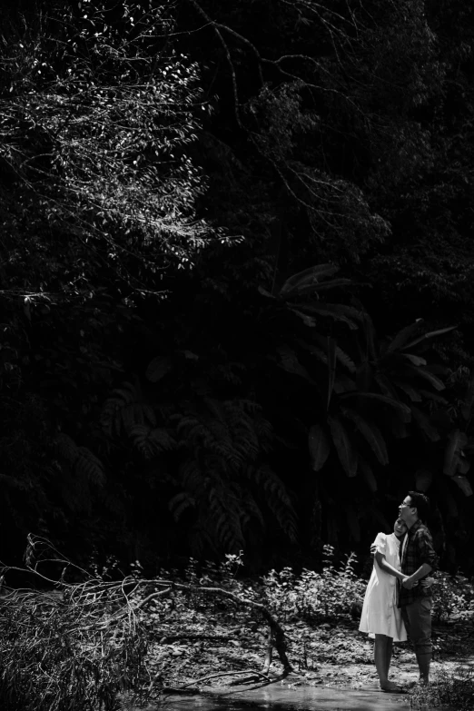 a man and woman are standing on a path near some plants