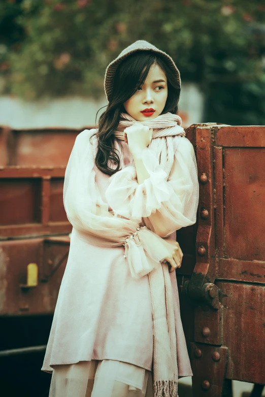 a young woman stands near an old wooden box