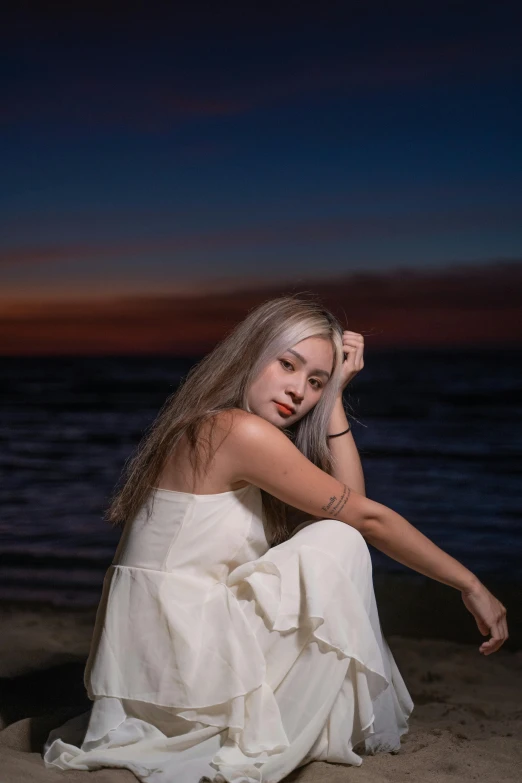 a girl sitting on the beach posing for the camera