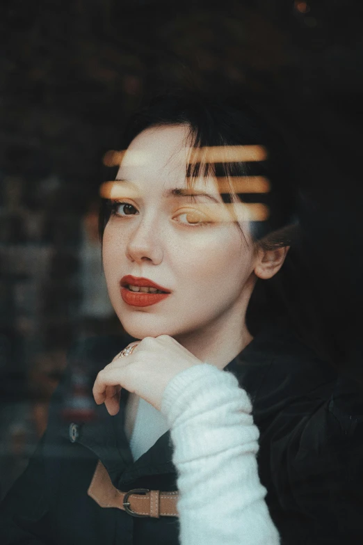 the young woman is staring into the window with her hand under her chin