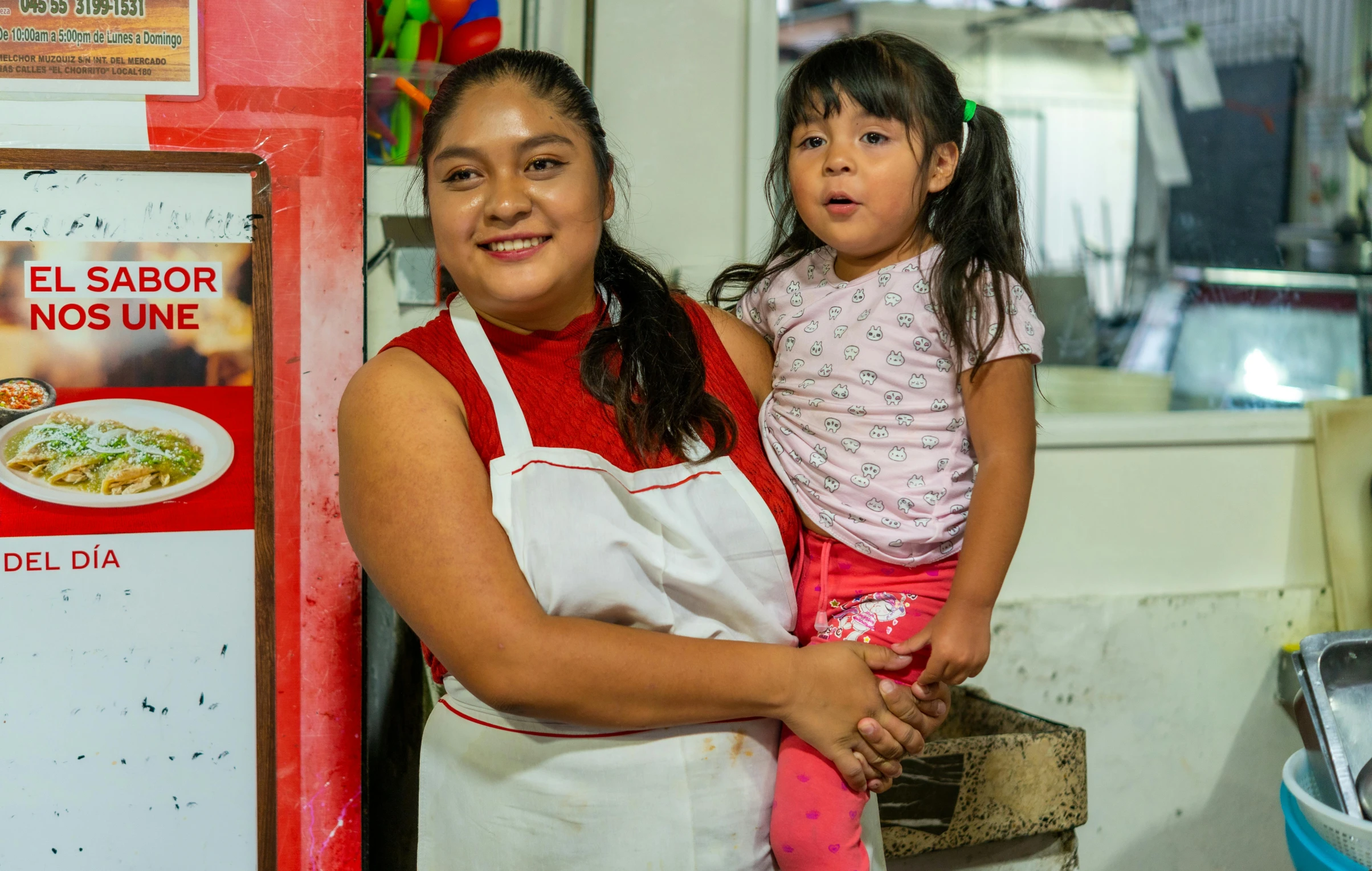 the woman with the child is posing in front of a menu