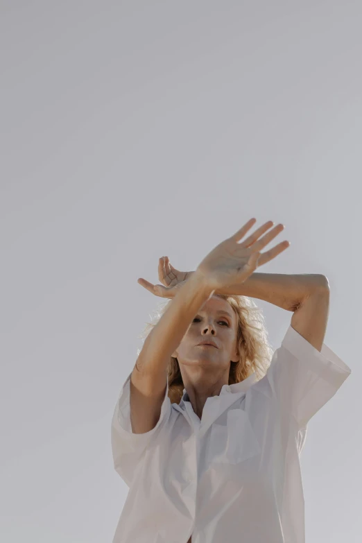 a woman in white shirt holding up her hands to the sky