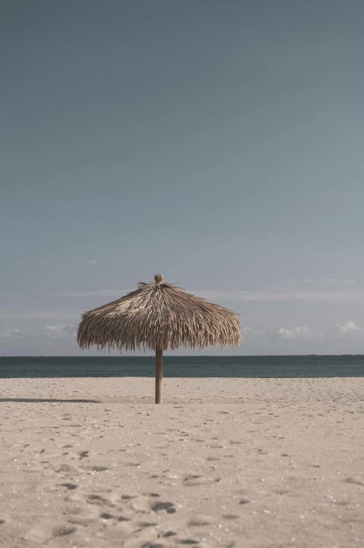 a gazebo is on the beach with footprints all around it