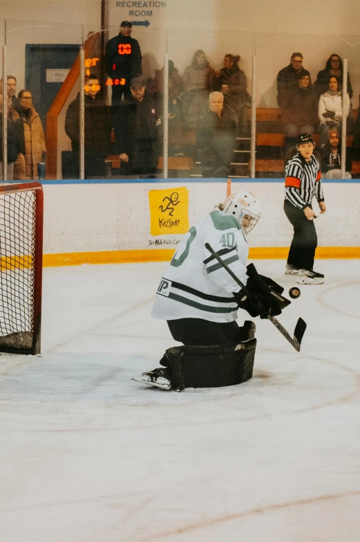 referee watching goaltender about to leave an ice rink