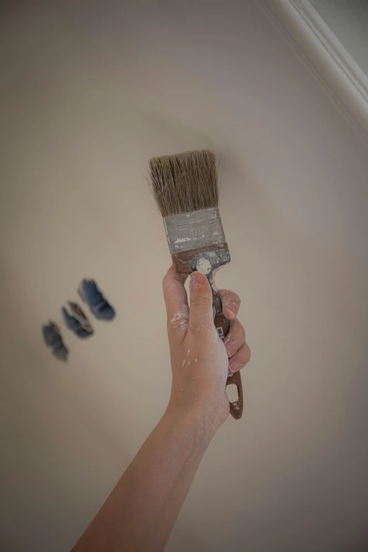 a person holding up a paint brush near shoes