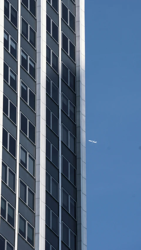 a large building has a single plane flying next to it