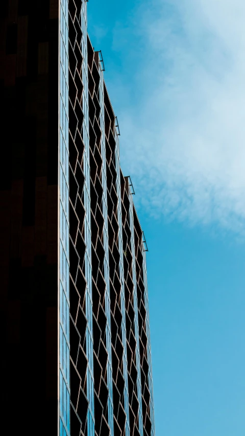 a tall skyscr with windows against a bright blue sky