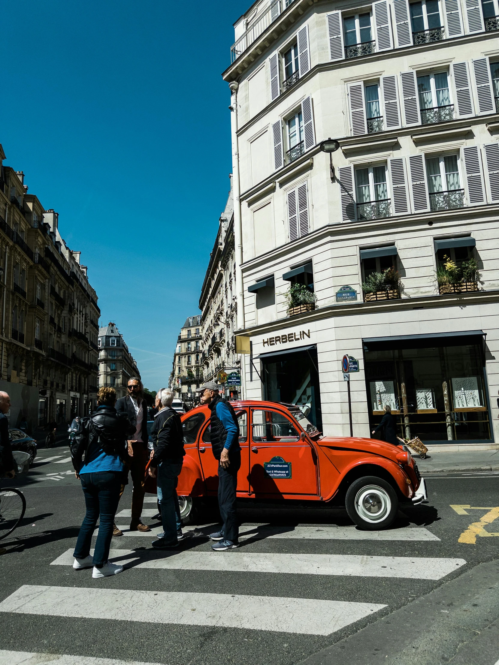 an orange car driving down a busy city street