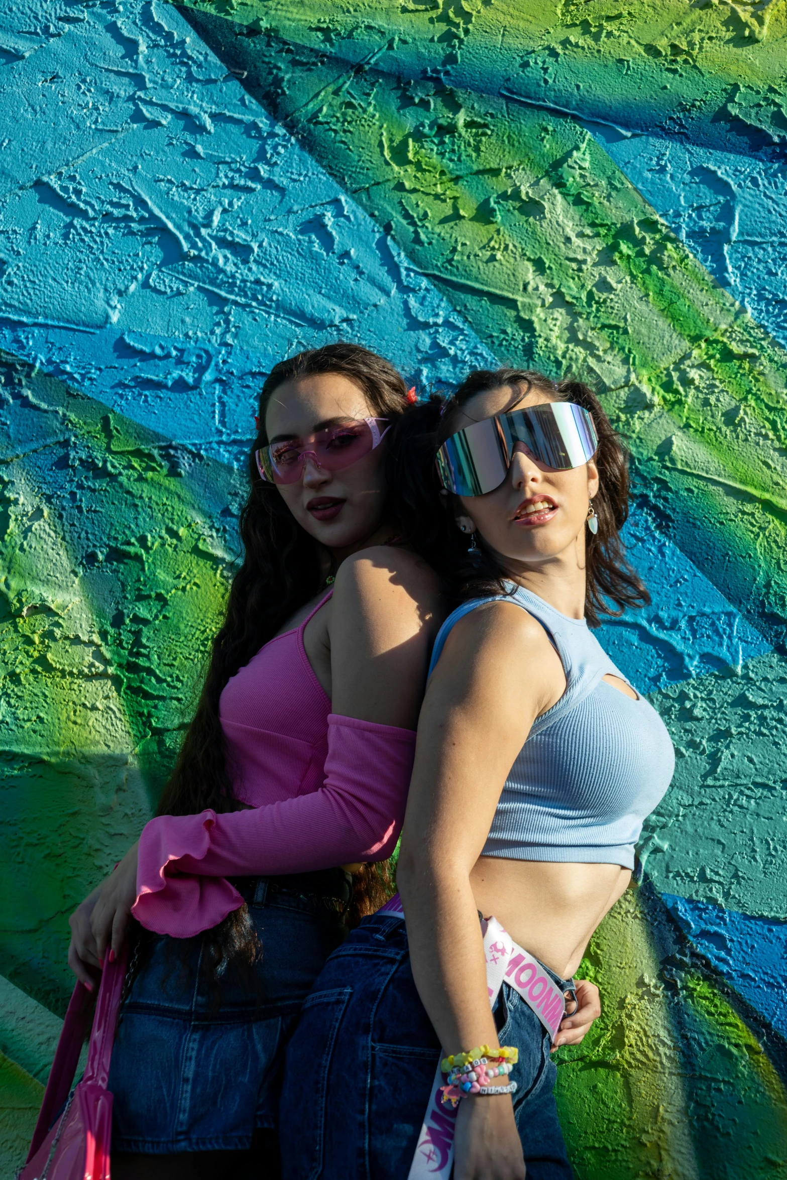 two women wearing sunglasses standing near a painting