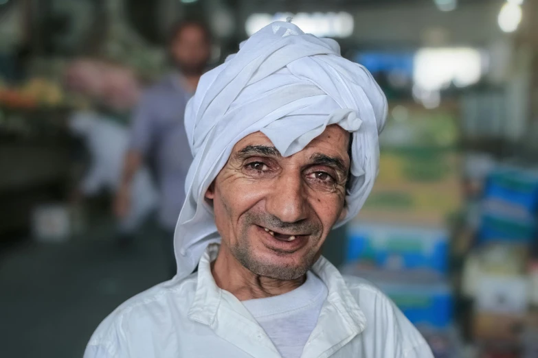 a man wearing a white turban smiles at the camera