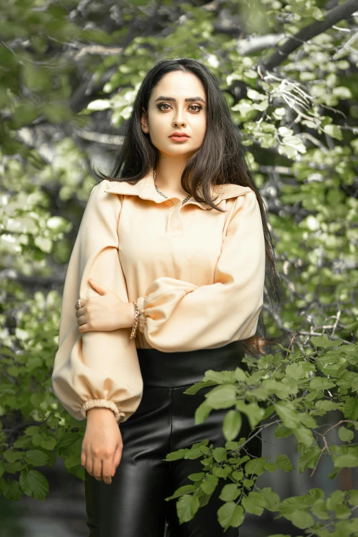 a woman in leather pants, standing near some bushes