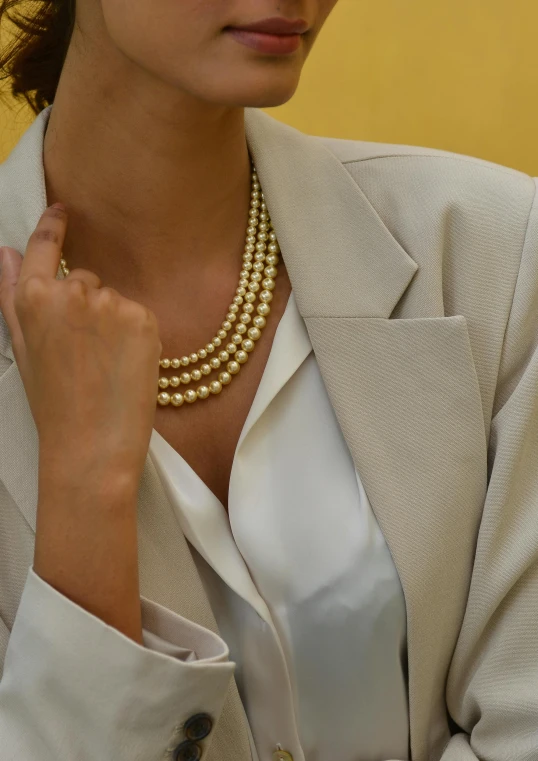 a woman in a white shirt and gold necklace