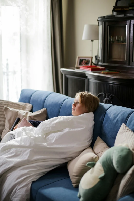 a little boy in a bed that is on top of a blue couch