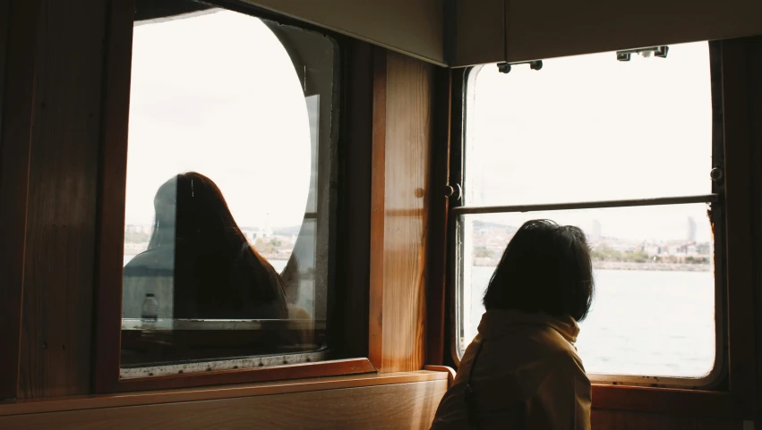 a woman staring out the window at the water