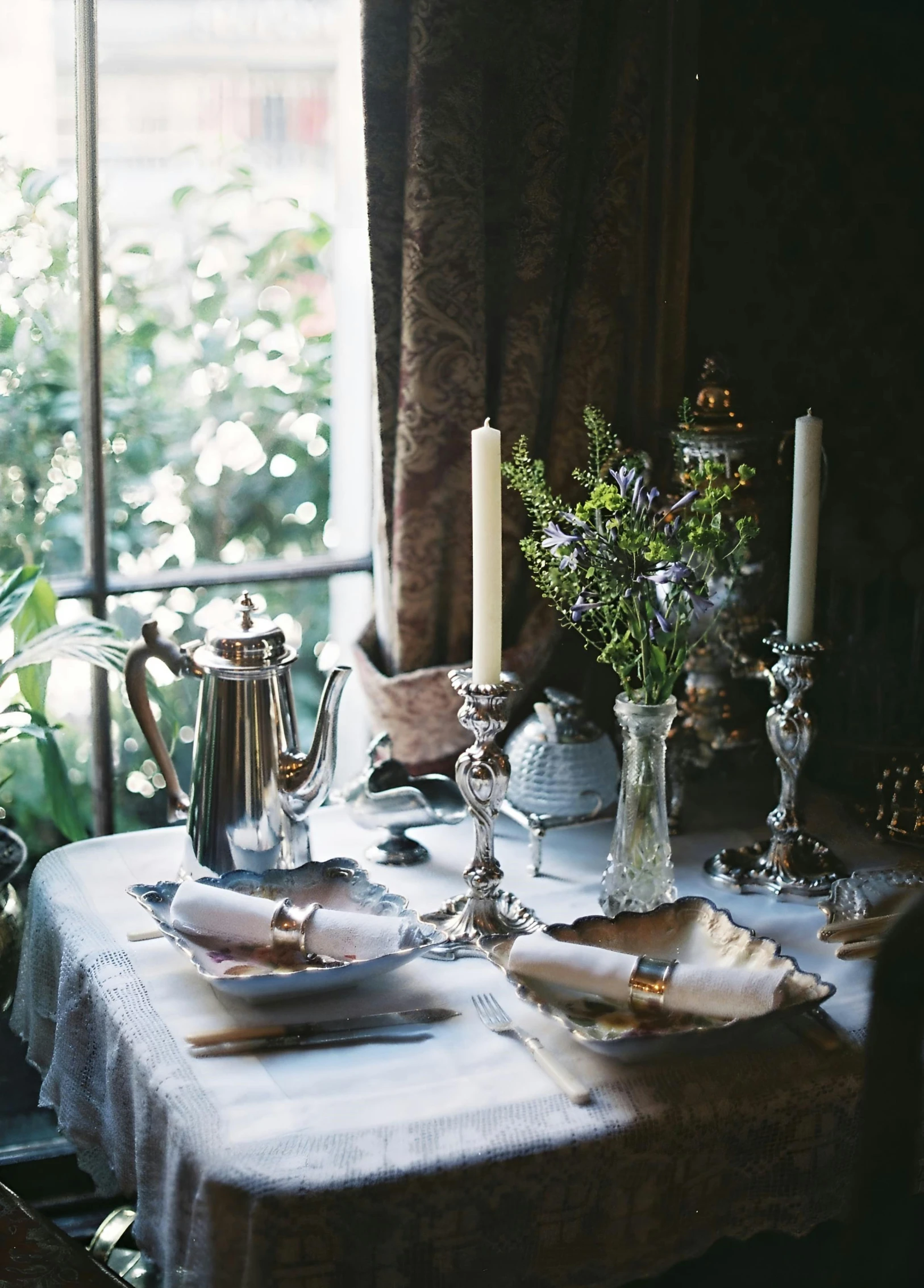 a table has flowers in vases, dishes, and silverware