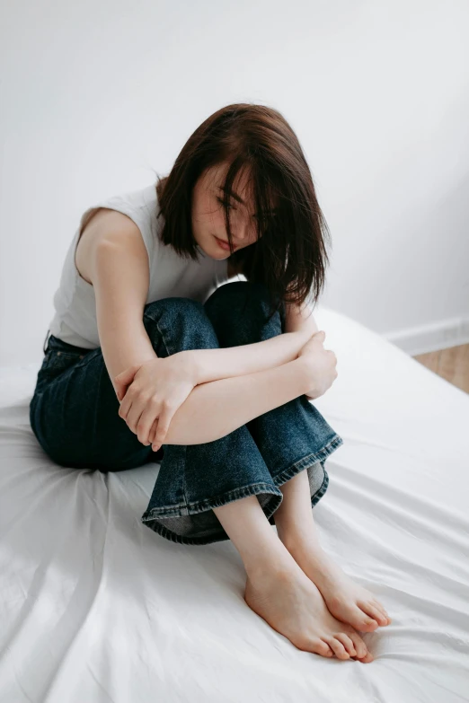 a young person is sitting on a white bed