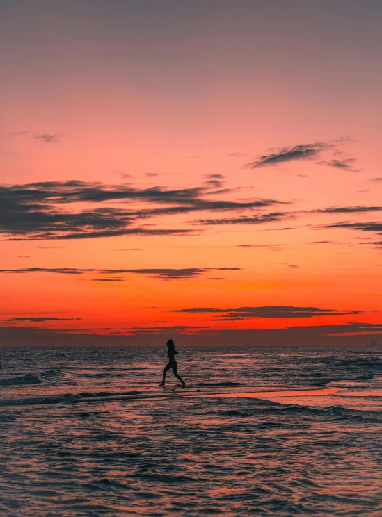 a person on surfboard in the water at sunset