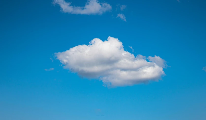 an unusual cloud is floating in the sky over an open field