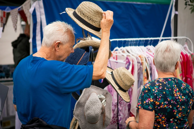 a man and woman shop for hats on a rack