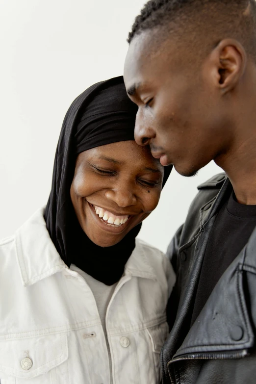 a man in a jacket and a woman in a headscarf smiling at each other