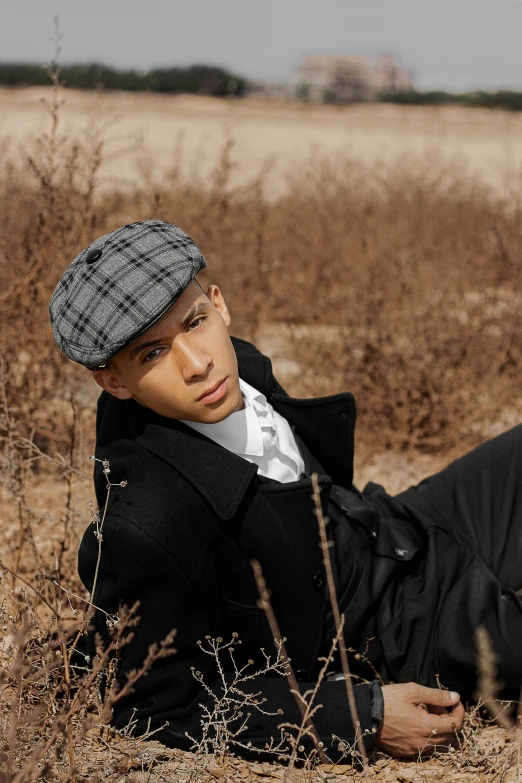 a young man laying on the ground in a hat