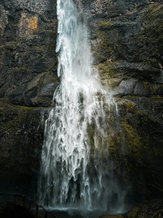 a very tall waterfall next to some mountains