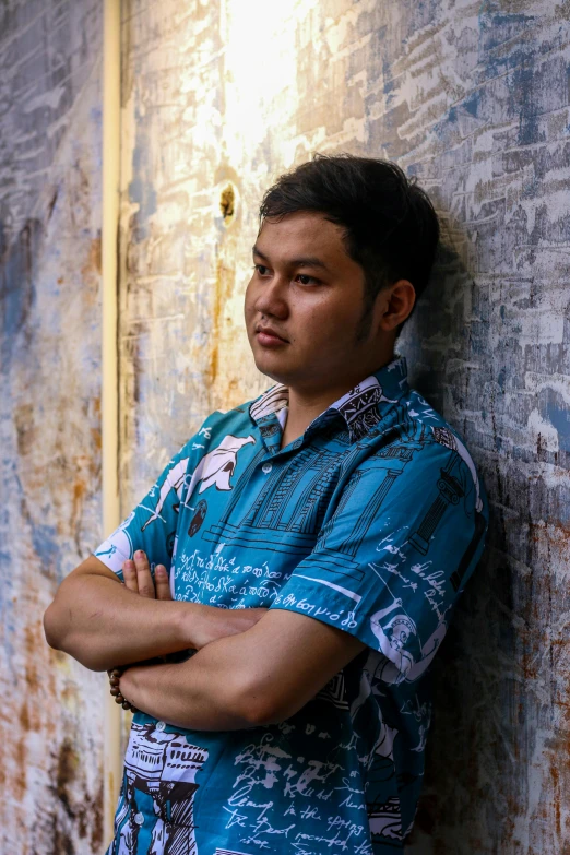 the man is posing against the wall with his arms crossed