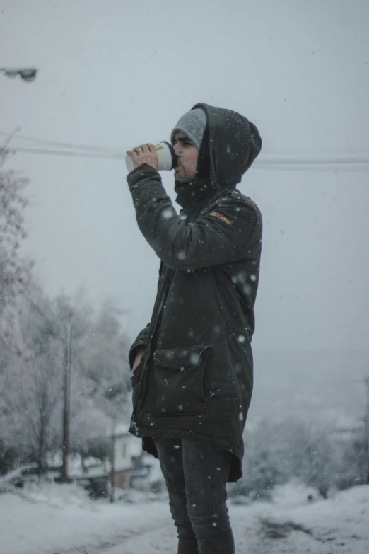 a person standing on a snowy road drinking soing