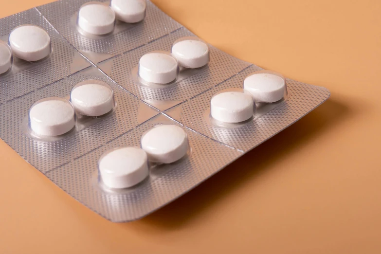 white pills in a contraption on top of a peach colored surface