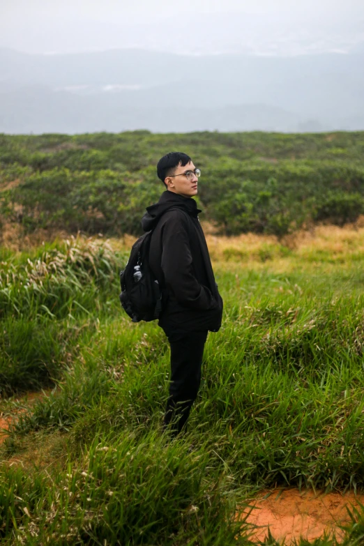 man with a backpack in a field staring away