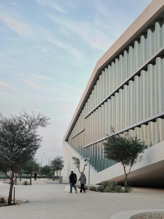 two people walking on a paved pathway next to a tall building