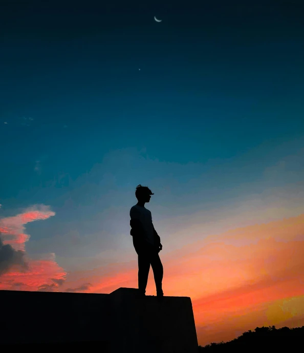 the silhouette of a man standing on a wall at sunset