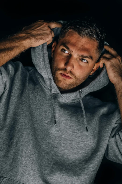 a man in a hoodie standing in the dark