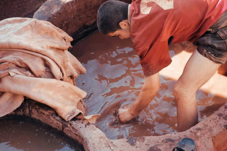 young man working in water filled pit with dirty clothes