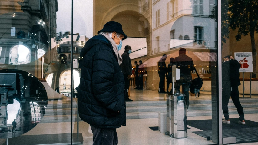 a person looking at his cellphone standing in front of a store window