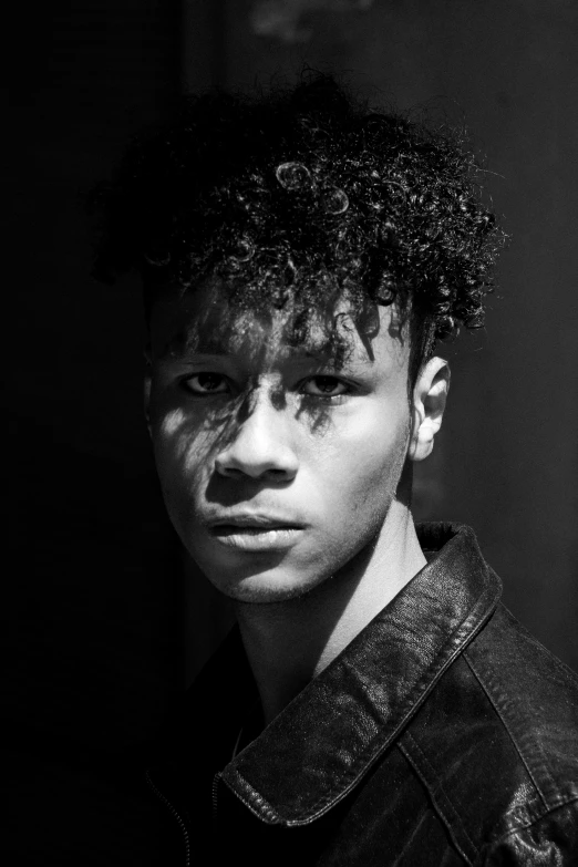 a boy is posing in front of a dark background