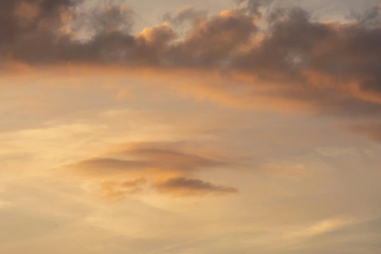 a plane in the air near clouds at dusk