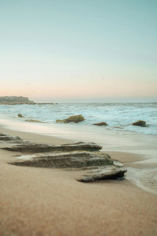 a beach next to the water with a rocky cliff at the end