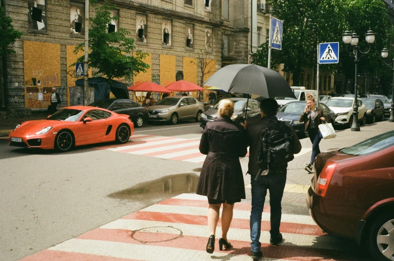 two people in street standing next to cars