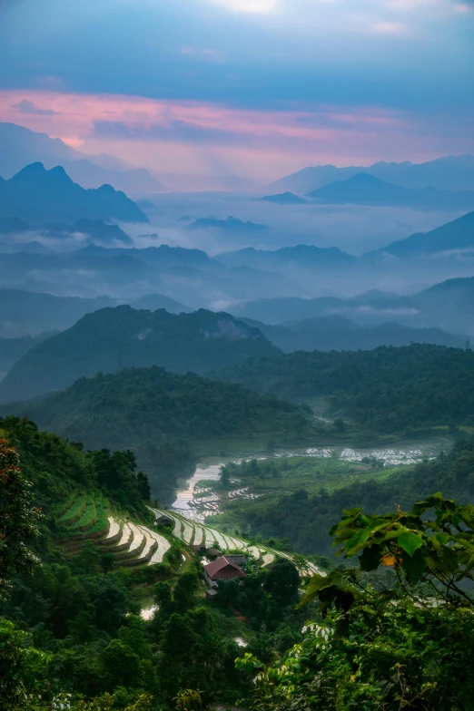 the mountains are covered in mist as the sun sets