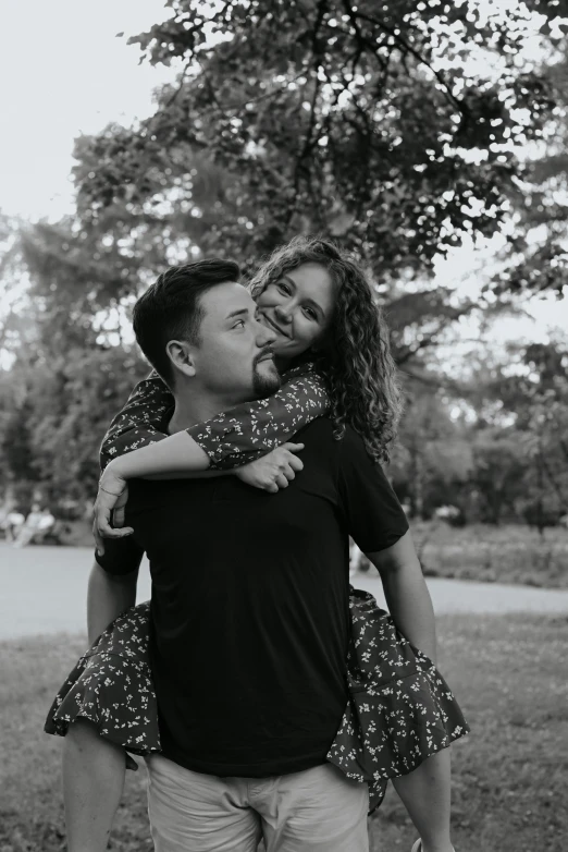 a man and woman hug each other as they walk through a park