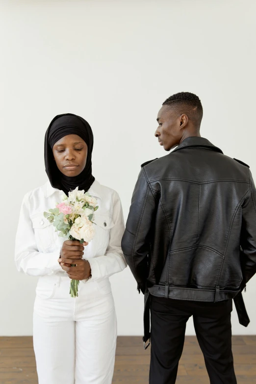 two people standing with a woman holding flowers